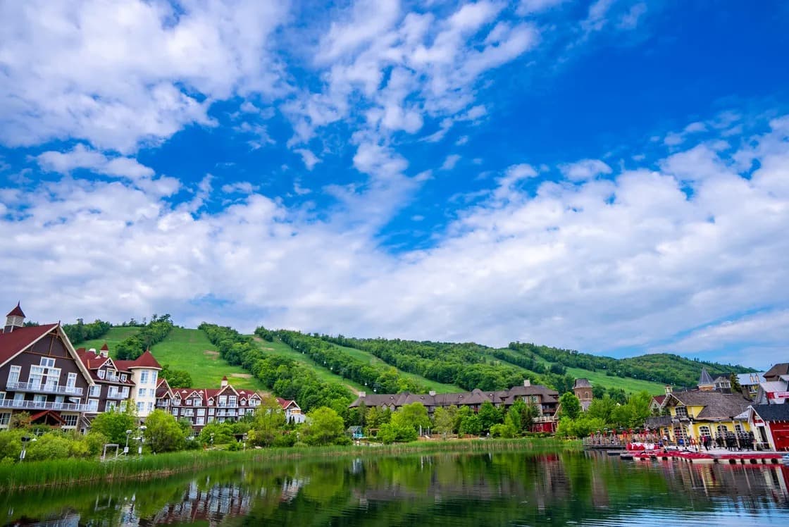 Blue Mountain Village with ski hills rising behind the pond